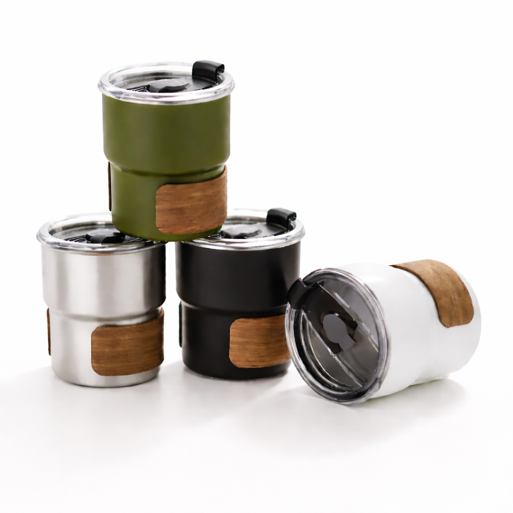 Mugs isothermes en inox avec bande bois, différents coloris, disposés en studio minimal sur fond blanc pour la collection Hydrivia.